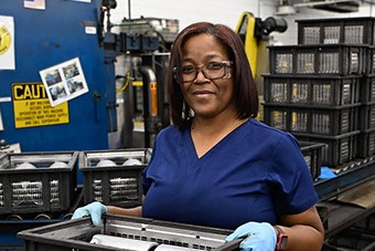 An S&C team member carries a tray of items to be sorted for proper recycling