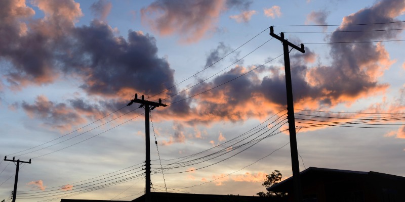Power lines in series above houses during sunset on cloudy day